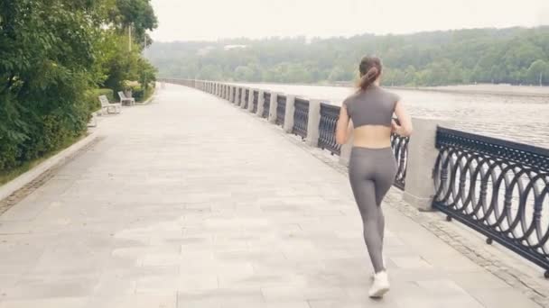 Mujer corriendo en el terraplén de la ciudad durante el entrenamiento de la mañana al aire libre — Vídeos de Stock