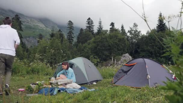 Туристична пара відпочиває на наметі в гірському пейзажі — стокове відео