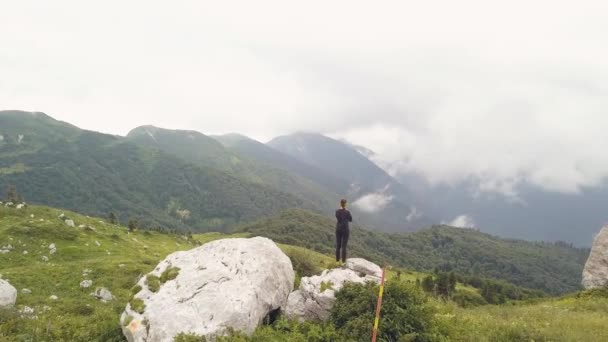 Mulher de pé em pedra grande na borda da montanha e desfrutando de uma bela vista — Vídeo de Stock