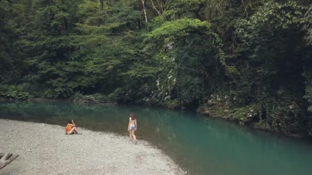 Donne che camminano e riposano sulla riva del fiume con acqua blu nella foresta estiva — Video Stock