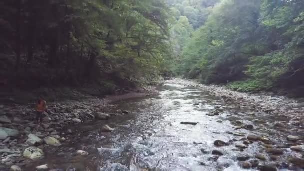 Žena na břehu řeky s tyrkysovou vodou v zeleném lese dron zobrazení — Stock video