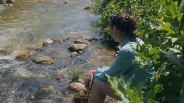 Ung kvinna sitter på floden stranden medan sommar vandring. Resor och turism — Stockvideo