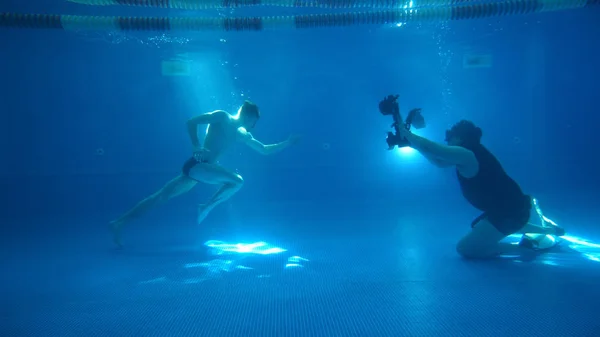 Fotografía submarina. Un modelo masculino está posando bajo el agua. Un joven guapo corre por el fondo. Behined las escenas. Fabricación de . —  Fotos de Stock
