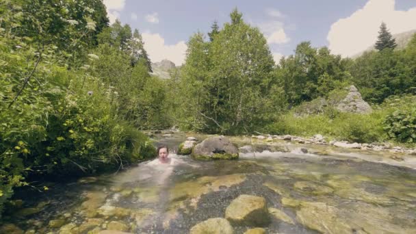 Junger Mann badet im erfrischenden Wasser des steinigen Flusses Zeitlupe — Stockvideo