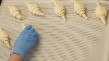 Fırın üstünde fırın mutfak pişirme için tepsideki kağıt kruvasan koyarak Baker