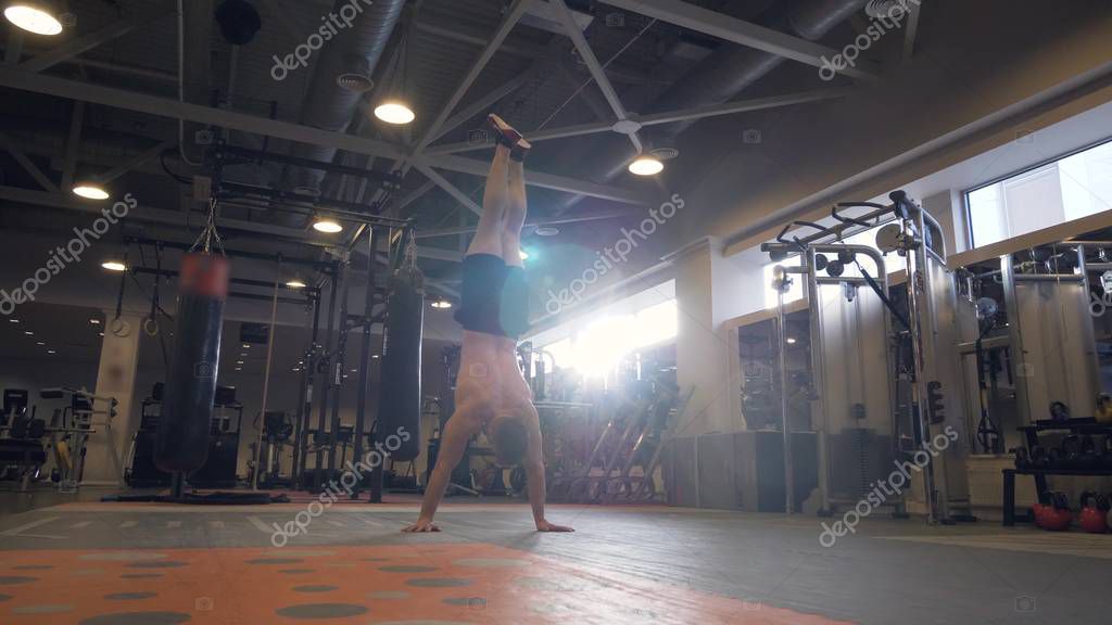 Hombre fuerte caminando con la mano durante el entrenamiento de crossfit en  el gimnasio