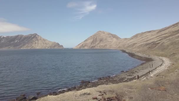 Vista aérea barriles oxidados en la playa del mar y el paisaje de montaña en destruido — Vídeo de stock