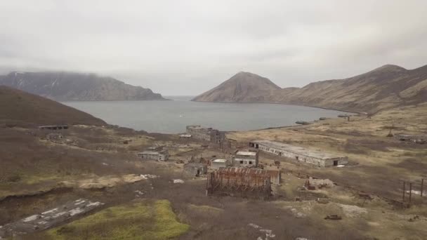 Зруйнована військова база в старому зруйнованому місті з видом на морську бухту і гірський безпілотник — стокове відео