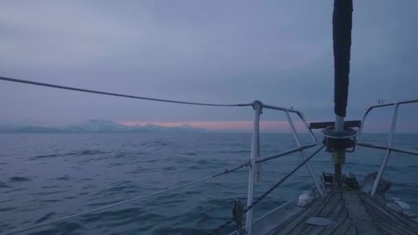 Ship sailing on sea while sunset in twilight sky and snowy mountain background — Stock Video