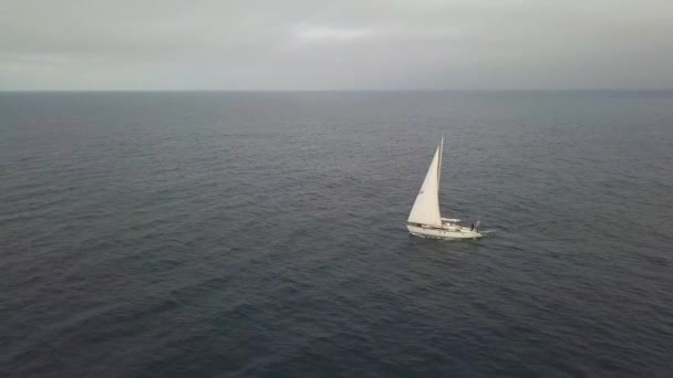Iate branco navegando no mar, enquanto o pôr do sol dourado no céu nublado vista drone — Vídeo de Stock