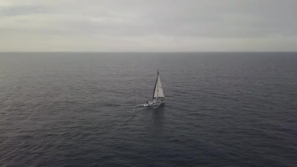 Luxejacht met witte zeil drijvend in de blauwe zee op skyline achtergrond luchtfoto — Stockvideo