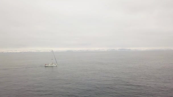 Вітрильний човен, що плаває в морі на засніженому гірському ландшафті вид з повітря — стокове відео