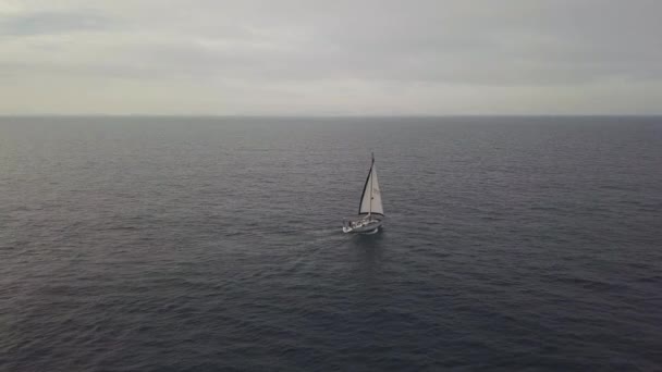 Розкішна яхта з білим вітрилом, що плаває в блакитному морі на фоні горизонту вид з повітря — стокове відео