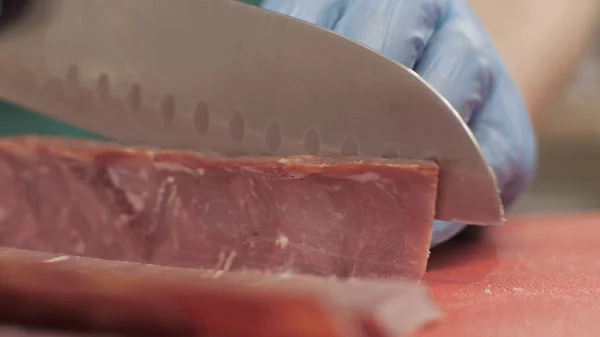 Manos cocinero utilizando cuchillo para cortar carne mientras se cocina en la cocina de cerca —  Fotos de Stock