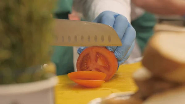 Szakács késsel használ vágás paradicsom szeletek kör és a darabokat étteremben kezében — Stock Fotó
