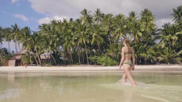 Mooie vrouw in bikini lopen op zee strand ant vallen in zoet water op hete dag. Lachende vrouw genieten van zeewater op zonnige dag. Meisje ontspannen in de Oceaan in paradise island. — Stockvideo