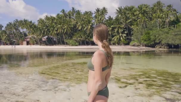 Aantrekkelijke vrouw in bikini lopen op kristalhelder zeewater op paradijs strand. Gelukkige vrouw genieten van water van de Oceaan op tropisch eiland. Zomervakantie aan zee strand. — Stockvideo