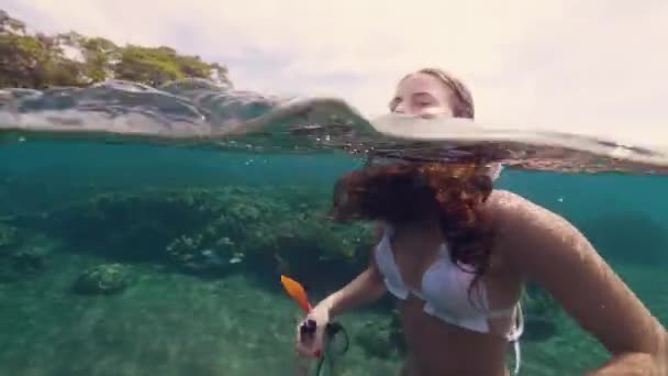 Mujer feliz con máscara de snorkel y tubo sonriendo y nadando en vista a la línea de flotación del mar. Mujer alegre nadando en el mar con máscara de snorkel. Vista submarina. Deportes acuáticos y mundo marino . — Vídeos de Stock