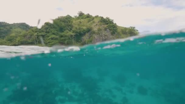 Tropisk ö och blå havet vatten vattenlinjen Visa. Gröna ön och stänk turkost havsvatten. Underwater skytte blå ocean vatten på paradise beach bakgrund. — Stockvideo