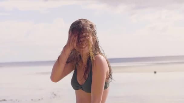 Ritratto bruna donna che scuote i capelli bagnati sulla spiaggia di mare. Donna allegra con capelli lunghi bagnati scuotendo la testa sul paesaggio della spiaggia sul mare. Bella ragazza in posa per la fotocamera sulla riva dell'oceano . — Video Stock