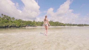 Bikinili kumsalda paradise resort, deniz suyu üzerinde yürüyen genç bir kadın. Düşük açılı görünüş. Yaz plaj, okyanus su üzerinde çalışan güzel bir kadın. Yaz tatili.