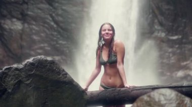 Tropikal yağmur ormanlarında akan dağ şelale üzerinde mayo güzel kadın. Gülümseyen kadın ayakta ve tropik şelale orman içinde kameraya poz bikini.