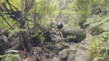 Buzlu yeşil orman arka plan üzerinde tropikal ormanda yürüyen turist kadın. Yağmur ormanlarında seyahat ve kayalık yolda yürüyen genç kadın. Vahşi orman orman ve tropikal doğa.