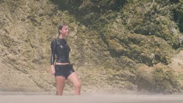 Mujer despreocupada en ropa mojada disfrutando de gotas de agua que caen de la cascada de montaña en la selva. Muchacha atractiva en el lago de montaña bajo el agua que fluye de los ríos tropicales en la selva tropical . — Vídeos de Stock