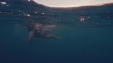 Mavi denizi ve altın güneş su yüzeyi parlıyor yüzme sualtı görüş genç kadın. Mayo wimming akşam gökyüzünde güneşte altın arka plan üzerinde mavi okyanus su hattı görünümü genç kız.
