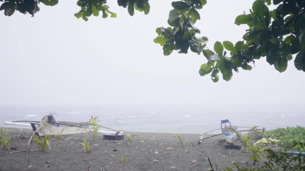 Träbåtar på sandstrand medan regn och storm i havet. Regn faller på stranden och fiske båt på stranden på bakgrunden mulen himmel och stormigt hav. — Stockvideo