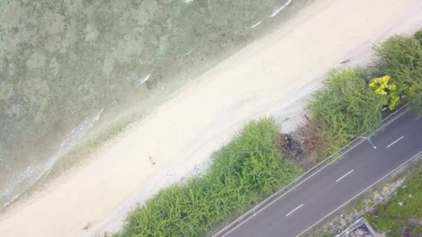 Widok z góry samochodem wzdłuż plaży i morza rozbryzgi wody na piaszczysty brzeg. Drone widok młodych relaksujący kobietę leżącą w piasku na plaży oceanu. — Wideo stockowe