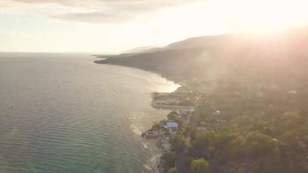 Günbatımı dağda deniz kıyısında hava peyzaj tropikal şehir üzerinde akşam. Drone görünümü altın güneş ışığında akşam günbatımı okyanus kıyısında şehir üzerinde dağlık üzerinde iken bulutlu gökyüzü. — Stok video