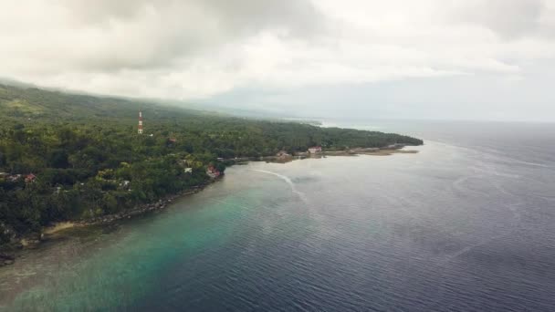 Letecký pohled na zelený tropický ostrov a tyrkysové moře na zamračená obloha pozadí. Krásná krajina shůry létající dron zelený ostrov na pobřeží oceánu. — Stock video