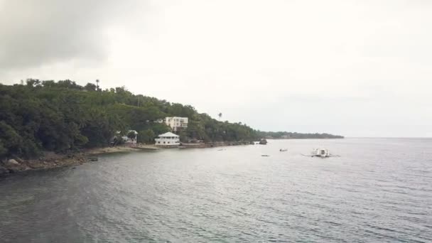 Navios e barcos flutuando no mar em fundo hotel turístico na costa tropical vista aérea. Vista de cima drone voando para ilha verde na praia do oceano em fundo céu nublado . — Vídeo de Stock