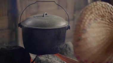 Şenlik ateşi üzerinde tencerede yemek yemek için fan ile ateş üfleme. Güveç geleneksel Asya köyde yakacak odun yanan üzerinde yemek hazırlama.