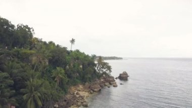 Resort otel tropikal palmiye ağacı üzerinde deniz kıyısında havadan görünümü arasında. Dron Adası ve okyanus bulutlu gökyüzü arka plan üzerinde yeşil palmiye ağacı görüntüle