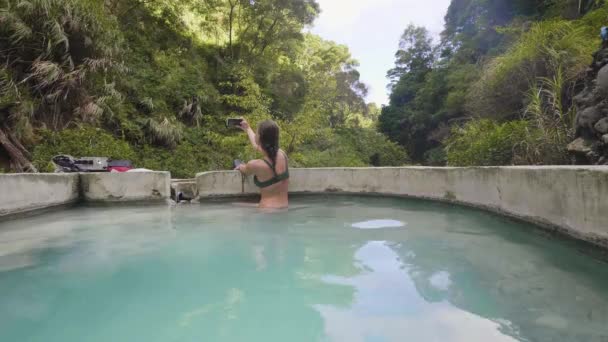 Turisztikai nő segítségével mobil selfie fotó a termálforrásból ásványi fürdő szabadtéri fürdő. Utazás blogger csinál mozgatható selfie, miközben termálfürdő természetes spa resort.. — Stock videók