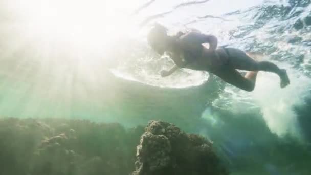 Mujer feliz con gafas para nadar bajo el agua buceando en el mar azul sobre el fondo del sol. Mujer joven nadando bajo el agua en el fondo del arrecife de coral . — Vídeos de Stock