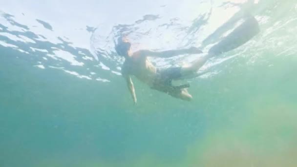 Young man swimming in snorkel mask and tube and shooting selfie video. Portrait man snorkeling in mask and snorkel under transparent sea water. — Stock Video