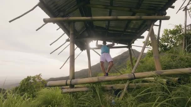 Bonito homem treinamento puxar para cima exercício na barra transversal de madeira ao ar livre. Homem atleta exercitando puxar ups na paisagem colina verde. Ginásio de treino . — Vídeo de Stock