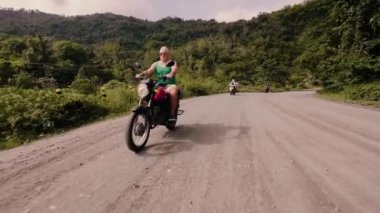 Yaz tatil seyahat ederken yolda motosiklet sürme komuta sizde. Yaşlı motosikletçi yeşil tepelerin ve yaylaları motosiklet üzerinde sürüş tropikal orman kaplı.