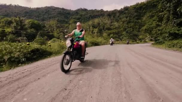 Idősebb ember, lovaglás a motorkerékpár közúti utazás, a nyaralás közben. Idős motoros vezetés, motorkerékpár, zöld dombok és a felföld borított trópusi erdő. — Stock videók