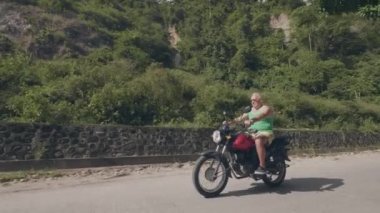 Yakışıklı adam yaz gününde motosiklet seyahat. Tropikal dağlık peyzaj üzerinde motosiklet sürme kıdemli adam. Moto seyahat konsepti.