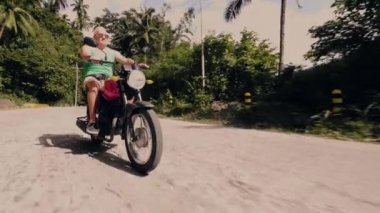 Tropikal orman manzara yolda motosiklet sürme kıdemli adam. Yaz tatilinde Moto gezisi sırasında motosiklet sürme yaşlı adam. Motosiklet yaşam tarzı.