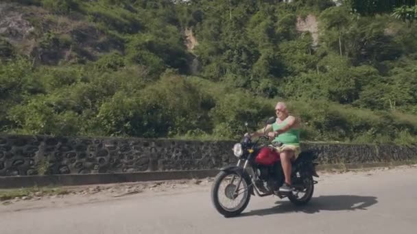 Bonito homem viajando de moto no dia de verão. Homem sênior andando de moto na paisagem tropical das terras altas. Moto conceito de viagem . — Vídeo de Stock