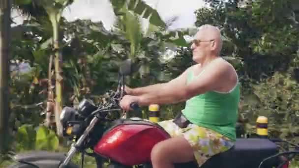 Uomo maturo che viaggia in moto nella campagna tropicale su verdi colline e paesaggio della foresta pluviale. Uomo anziano motociclista guida in moto in moto viaggi . — Video Stock