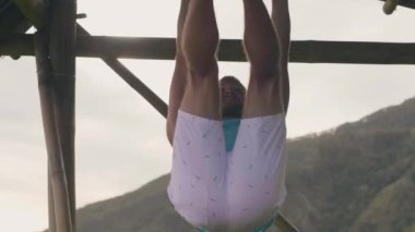 Atlet adam açık spor salonu egzersiz sırasında ahşap crossbar üzerinde karın egzersiz yapıyor. Fitness adam eğitim mide kasları yatay bar. Abs egzersiz.