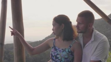 Aşıklar çift romantik seyahat ederken dağ zirvesinden doğal manzara izliyor. Genç kadın ve adam yaz seyahat ederken yeşil dağ kaplı tropikal orman arıyor.