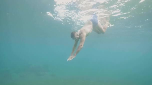 El hombre joven está buceando bajo el agua en el océano, vista lateral . — Vídeos de Stock