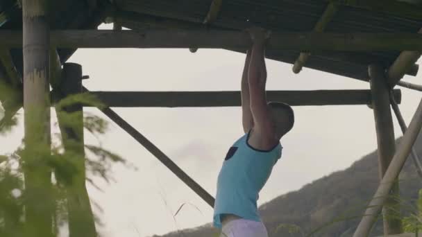 Entrenamiento de deportista tire de ejercicio en la barra horizontal sobre fondo de montaña verde. Culturista haciendo ejercicio pull up en el travesaño al aire libre. Estilo de vida deportivo . — Vídeo de stock